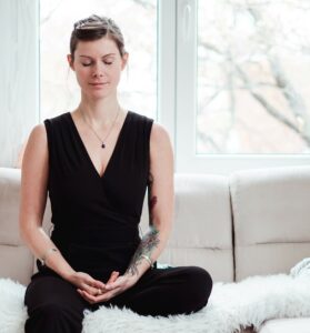 Offer - Frau sitzt auf Couch und meditiert